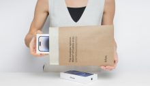Person holding a new smartphone in packaging.